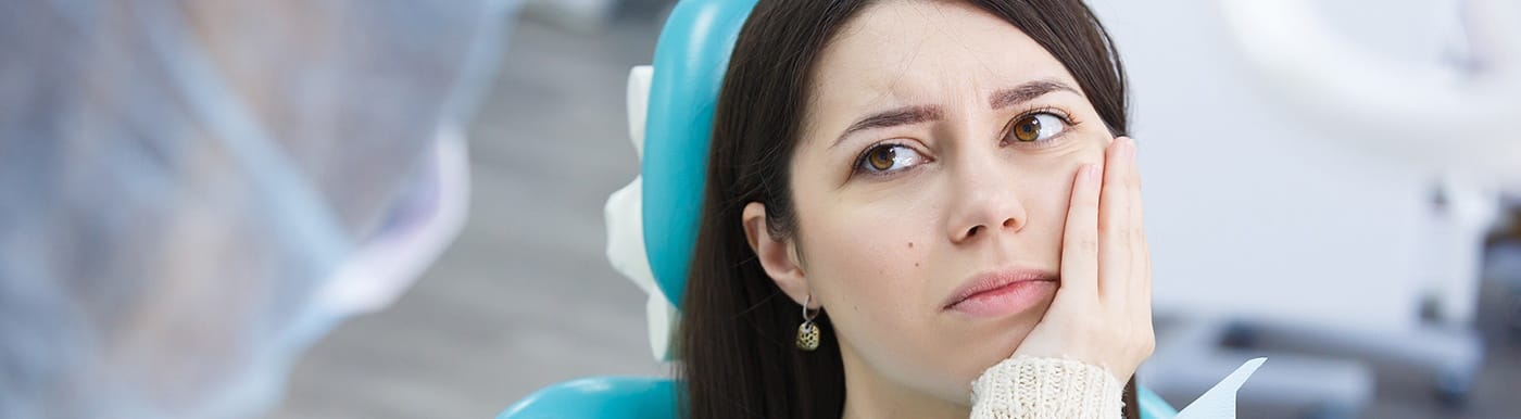 Woman in need of emergency dentistry holding cheek