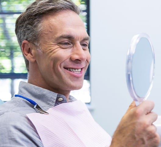 Man looking at smile after metal free dental crown
