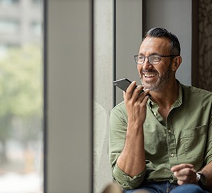 Man with glasses smiling on speaker phone