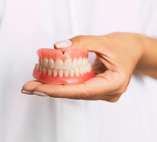dentist holding a set of full dentures 
