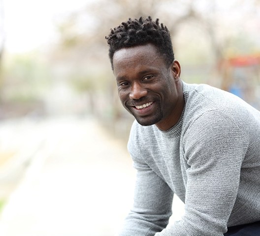 a smiling person sitting on a park bench