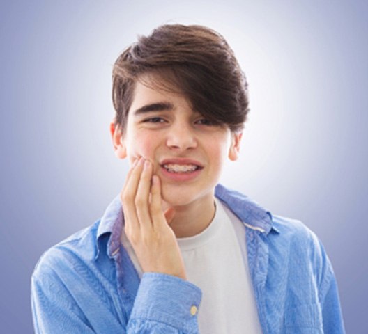 A teen rubbing his cheek due to an orthodontic emergency