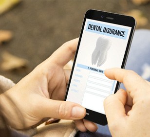 Woman looking up dental insurance coverage for dental implants on her phone 