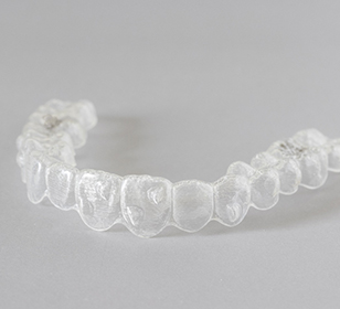 Closeup of clear aligner on grey surface