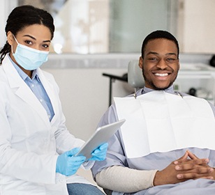 Dentist and patient smiling next to each other in office