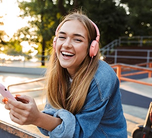 Teen girl smiling while listening to music outside