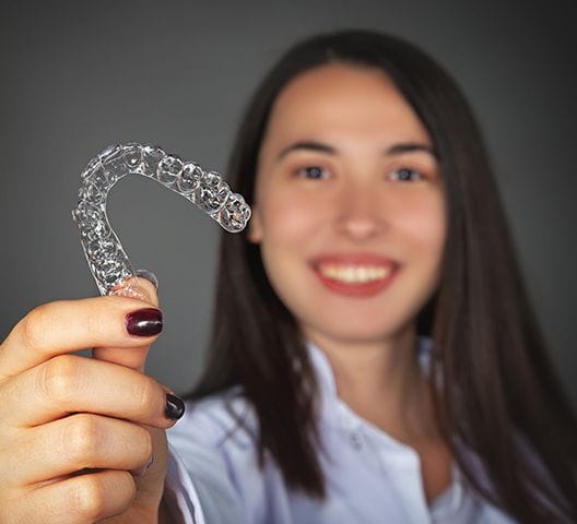 Woman holding up Invisalign tray