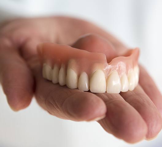 Hand holding a full denture