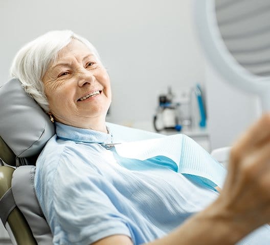 Woman looking at smile after dental implant tooth repalcement