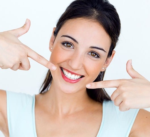 Woman pointing to healthy smile after scaling and root planing periodontal therapy