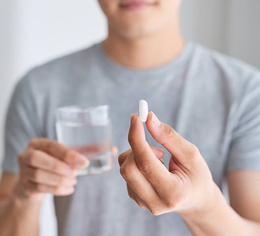 Man holding antibiotic pill for gum disease treatment