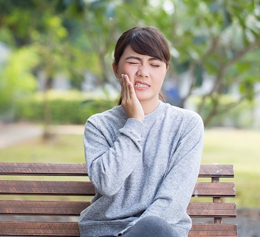 Woman in need of root canal therapy holding cheek