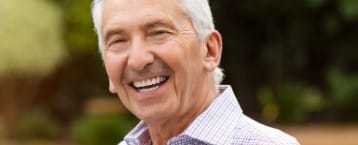 Older man smiling after replacing missing teeth