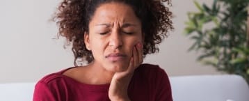 Woman in need of emergency dentistry holding jaw