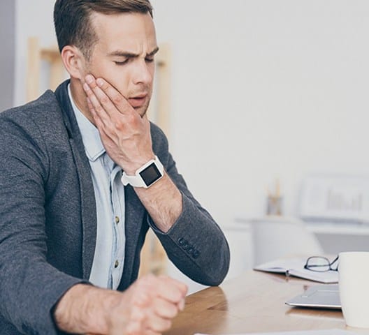 Man sitting at desk, in pain due to toothache
