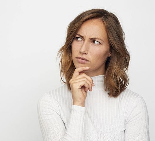 Frowning woman in white shirt, wondering why her toothache disappeared