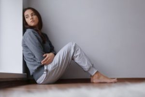 Depressed young woman sitting on floor