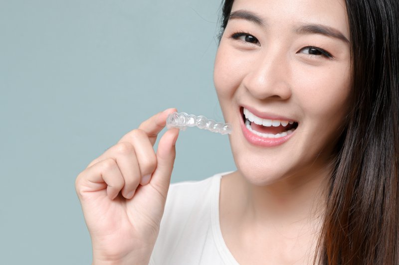 person holding Invisalign and smiling