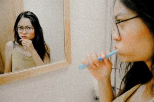 Woman brushing her teeth in her bathroom.