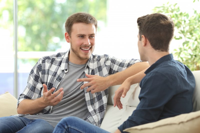 Friends talking while one wears Invisalign aligners