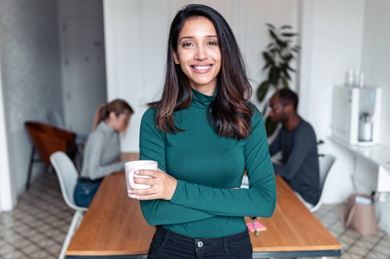 Woman smiling with Invisalign aligners in front of a business table