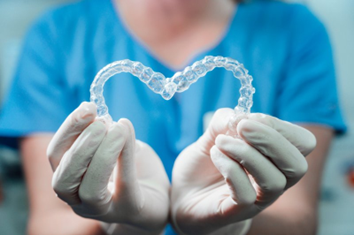 Dentist holding Invisalign aligners in the shape of a heart