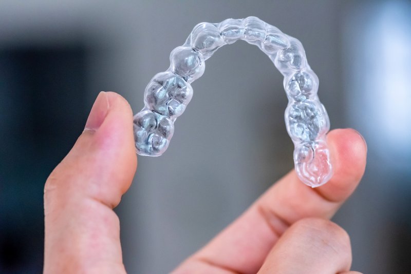 a person holding an Invisalign aligner